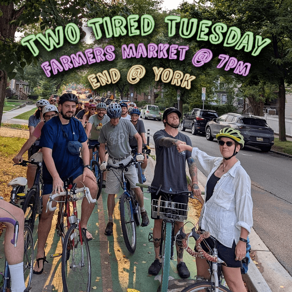 Two Tired Bicycle Club riders gathered with their bikes on a tree-lined street